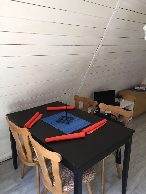 A dining area with a black table, wooden chairs, and a blue placemat.