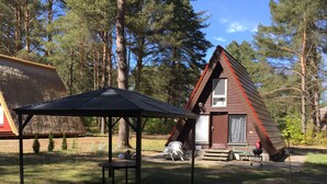 A cabin with a sloped roof, a covered picnic table, and a small porch.