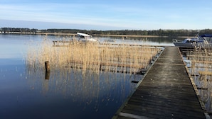 A wooden dock extending into calm water with boats docked on the right.
