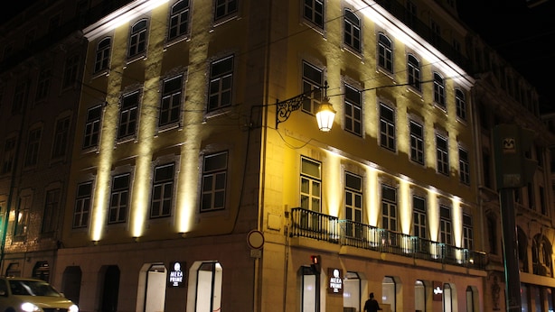A multi-story building with illuminated windows and a visible entrance. - MeraPrime Gold Design Hotel (Lisbon)