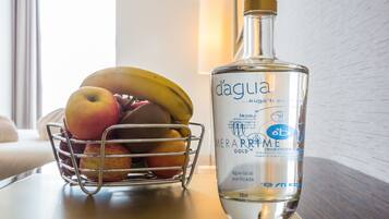 Una botella de agua junto a una cesta de frutas sobre una mesa.