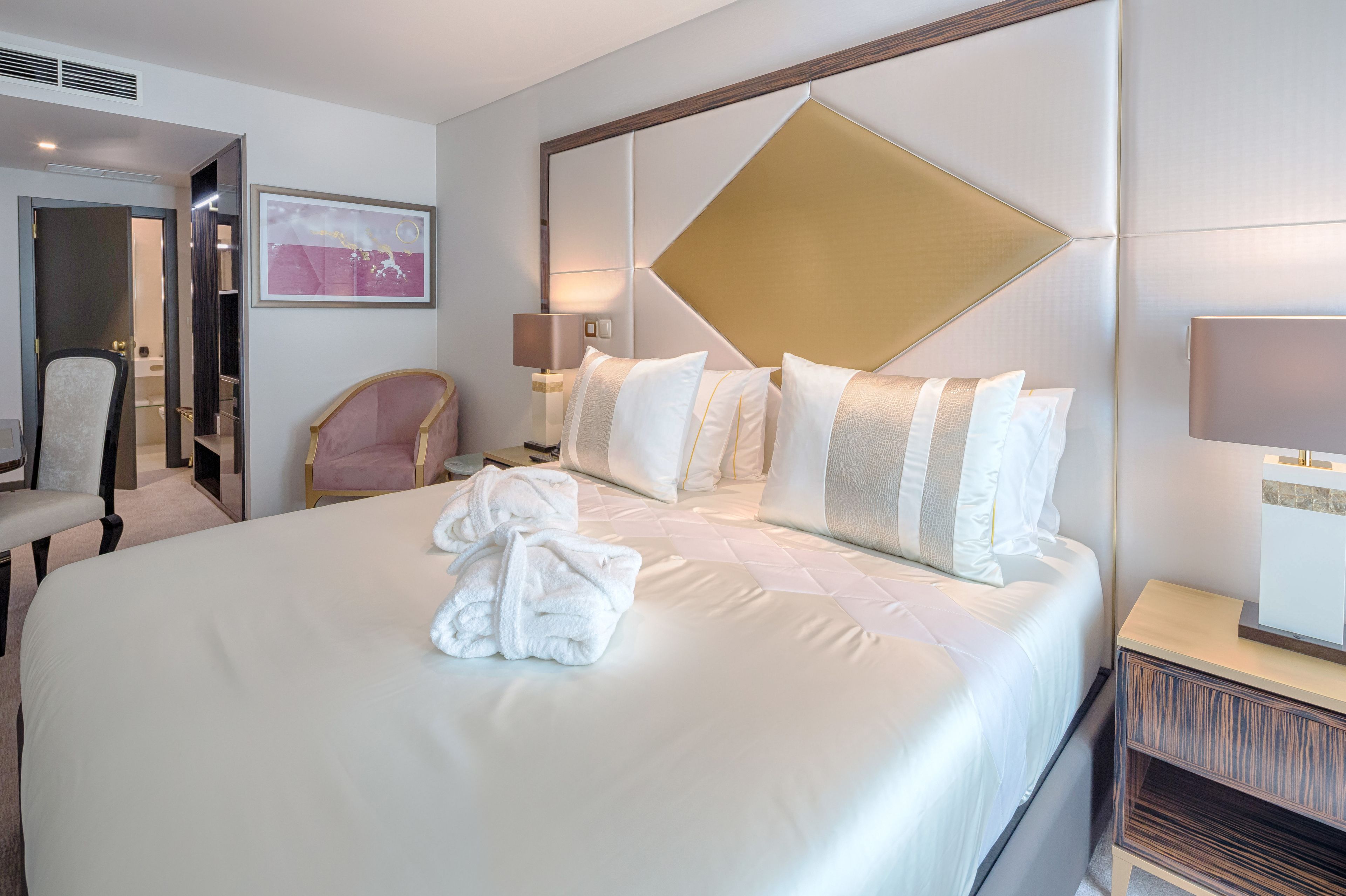 A hotel room with a large bed, a chair, a desk, and a mirror.