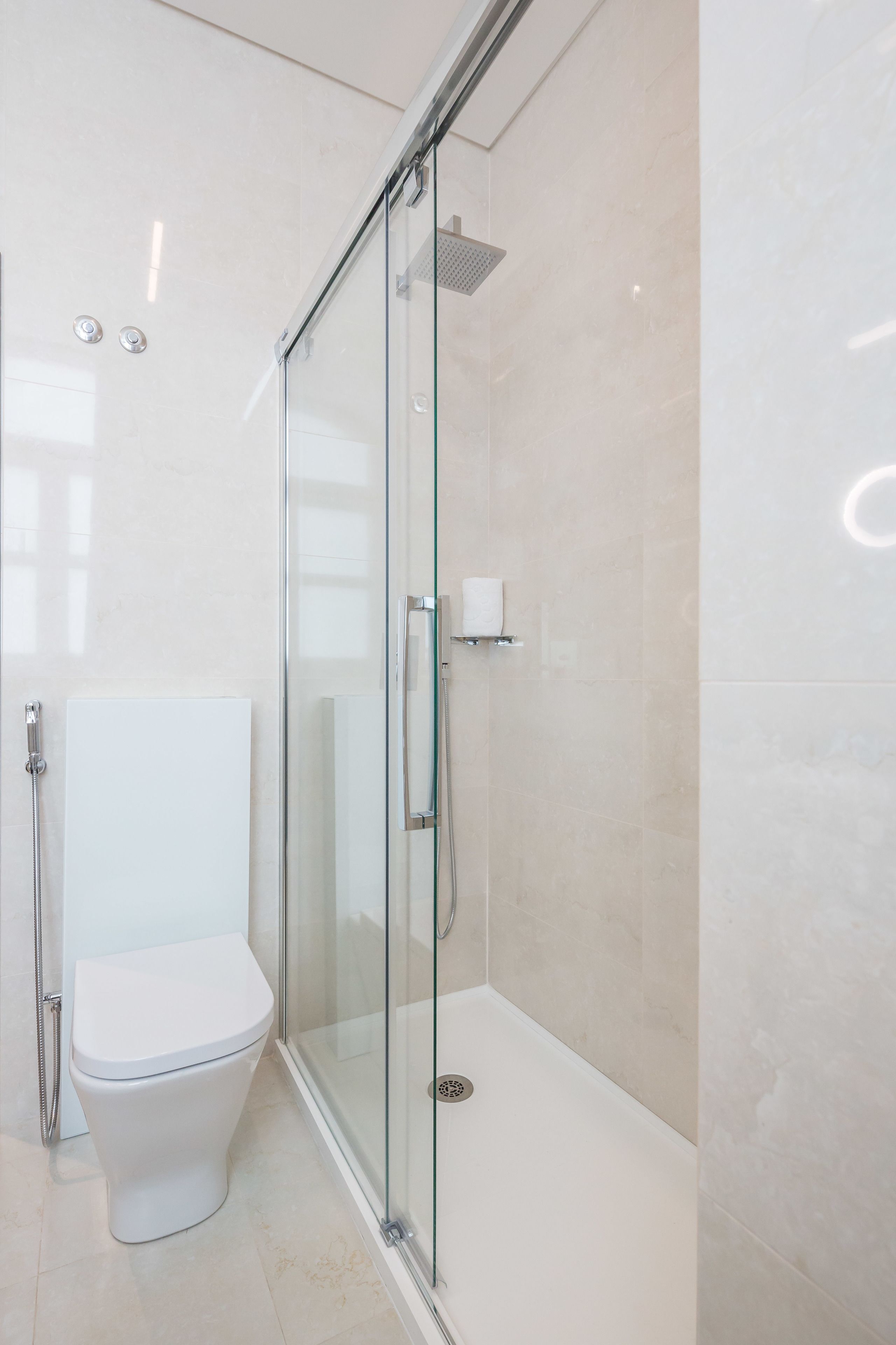 A modern bathroom with a glass-enclosed shower, a toilet, and a white sink.