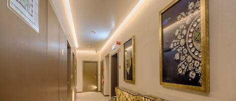 Un pasillo de hotel largo, con un extintor y un cuadro en la pared.