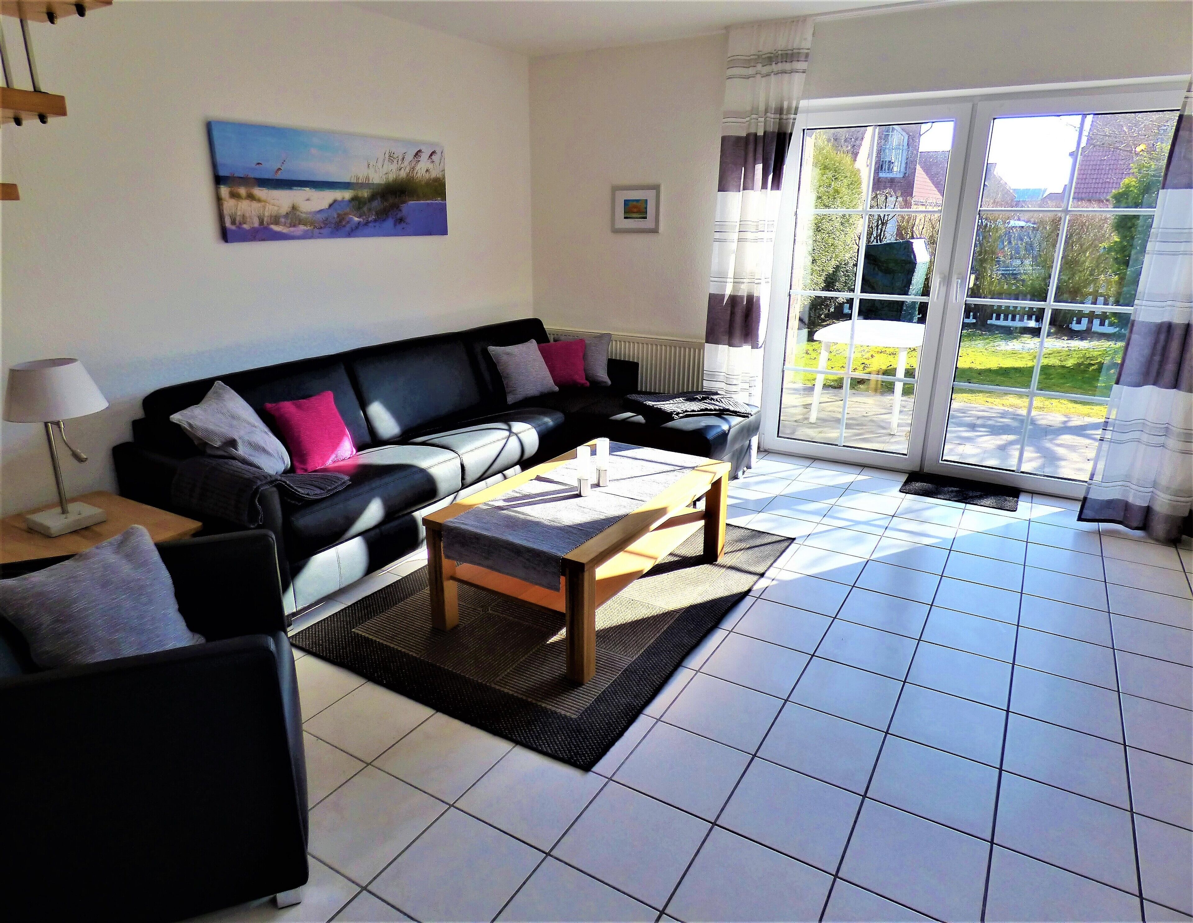 A living room with a black sofa, a wooden coffee table, and a painting on the wall.