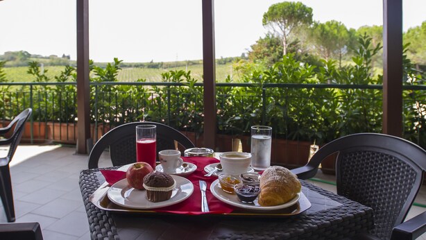Una mesa preparada con alimentos para el desayuno en un balcón con vistas a un paisaje verde y exuberante.