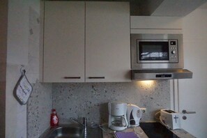 Eine Küche mit Mikrowelle, Kaffeemaschine, Toaster und Spüle.