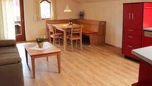Ein kleiner Wohnraum mit einem Holztisch, einer Bank und einem roten Schrank.