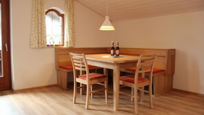 Ein Essbereich mit Holztisch und -stühlen, einer Hängelampe und einem fenster mit Vorhängen.