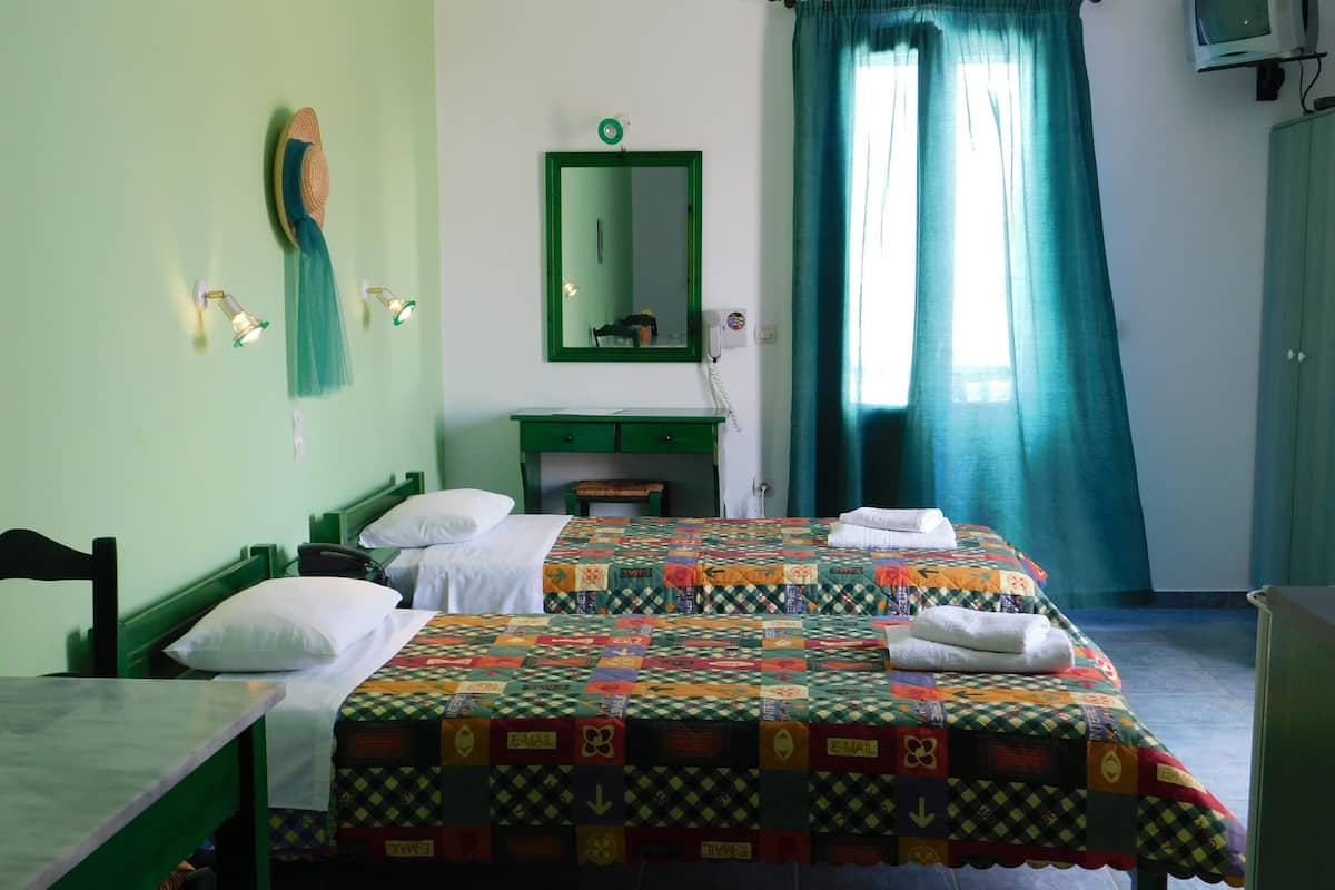 A room with a bed, a desk, a chair, a mirror, and a window with curtains.