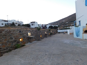 Un village côtier aux murs de pierre et aux bâtiments blancs, doté d’un sentier pavé et d’un petit espace aménagé pour s’asseoir.