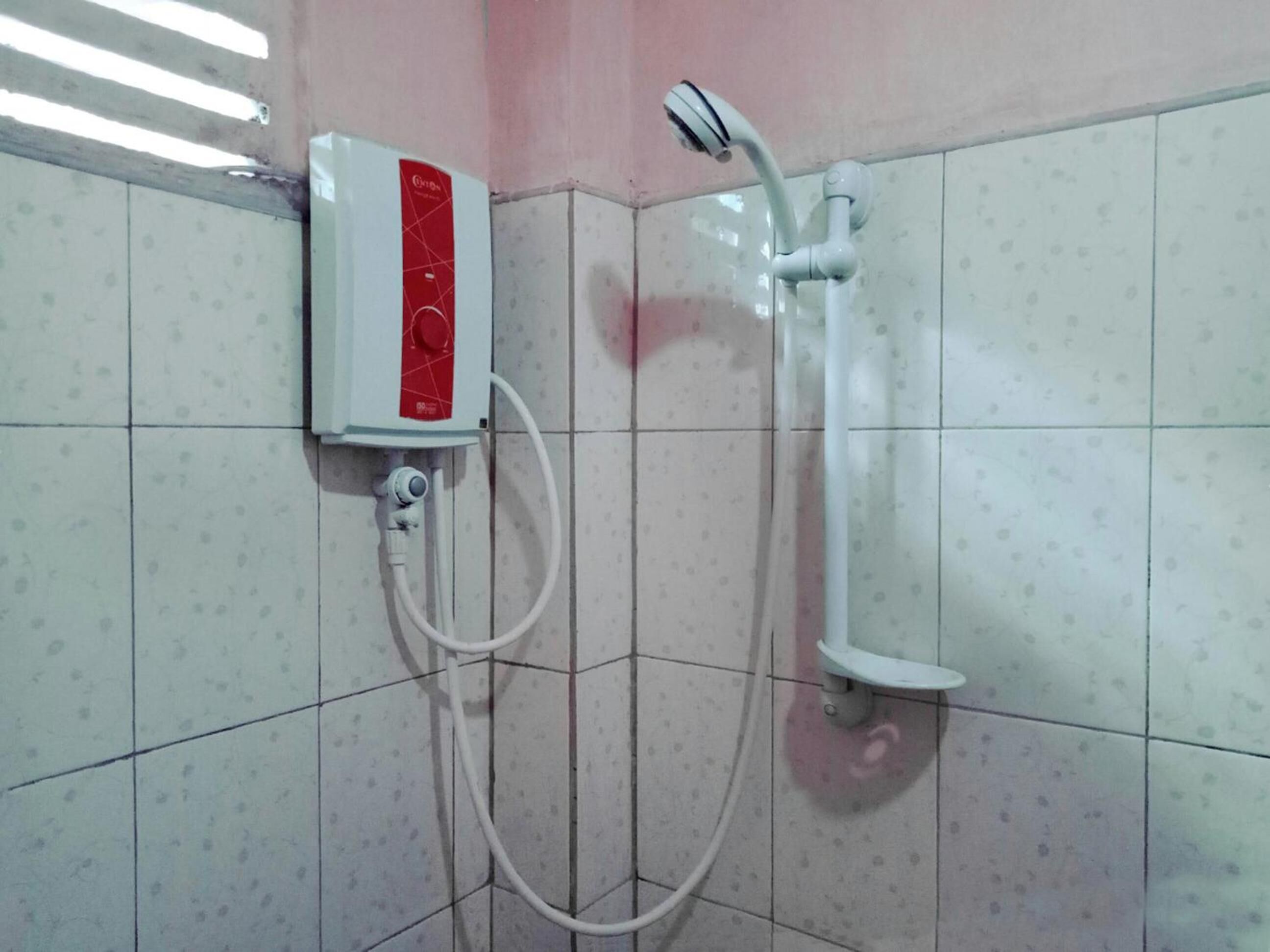 A shower area with a handheld showerhead and a wall-mounted control panel.