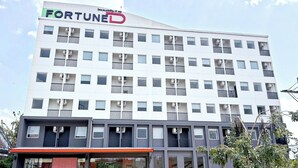 Ein mehrgeschossiges Gebäude mit einem markanten 'FORTUNED'-Schild, das moderne Architektur mit Balkonen und Klimaanlagen aufweist.