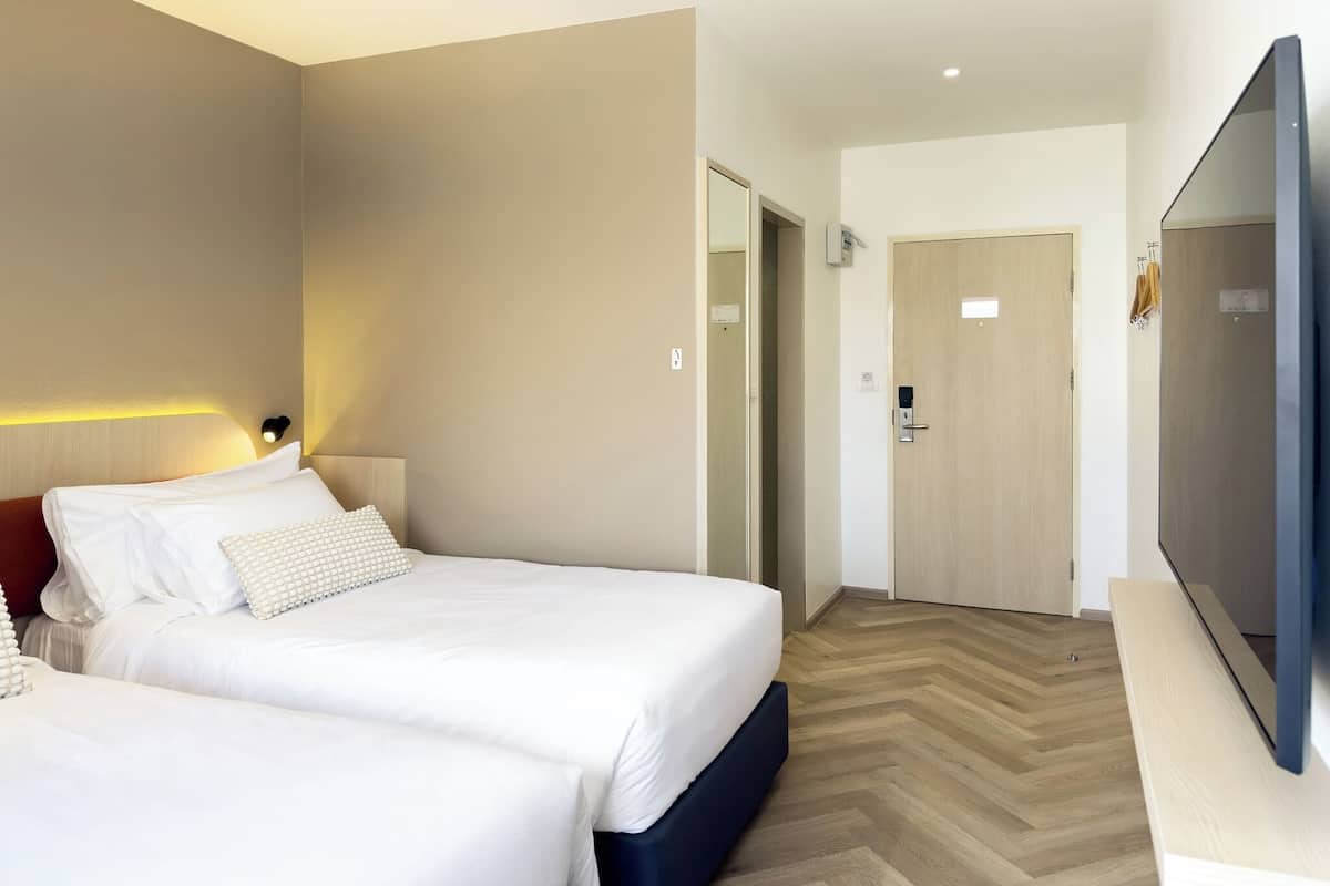 Une chambre d’hôtel avec un lit, une télévision et un plancher en bois.