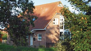Una casa a due piani in mattoni con tetto spiovente, un piccolo portico e una porta d'ingresso ben visibile.