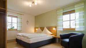 Ein Schlafzimmer mit einem Bett, Nachttischen, einem Sessel und einem Fenster mit Jalousien.