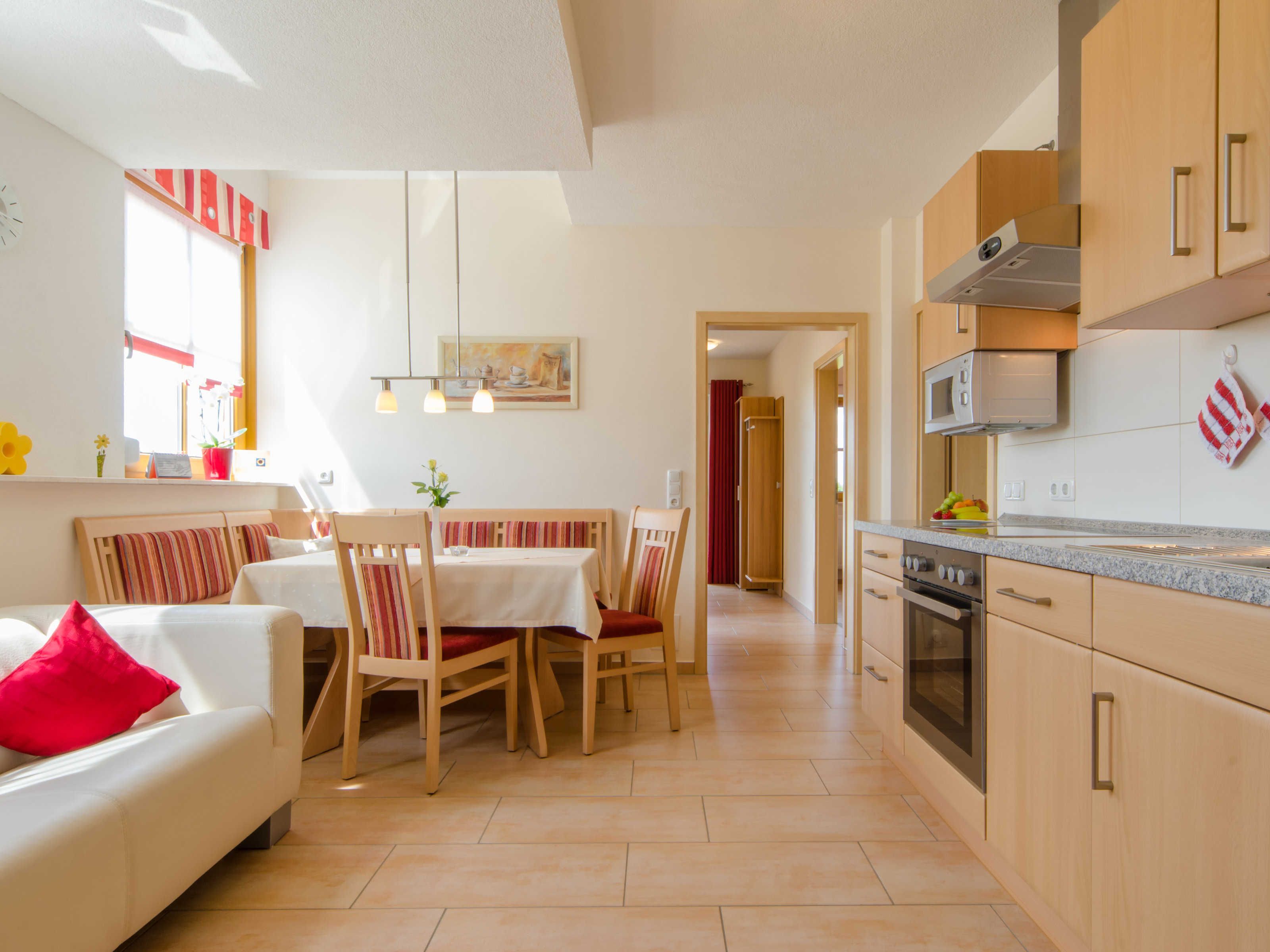 Una cocina moderna con armarios de madera, horno integrado y un comedor con sillas a rayas y una mesa.