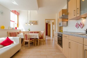 A modern kitchen with a dining area, wooden cabinets, and a red and white striped towel.