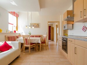 Une cuisine moderne avec des meubles en bois, un four encastré et un coin repas agrémenté de chaises à rayures et d’une table.
