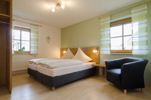 A bedroom with a bed, bedside tables, a chair, and a window with blinds.