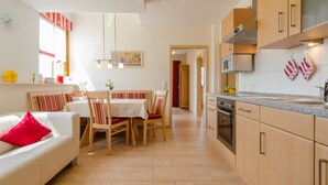 Eine moderne Küche mit Essbereich, Holzschränken und einem rot-weiß gestreiften Handtuch.