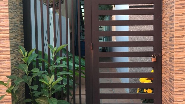 Una entrada protegida por una reja con una planta en maceta a un lado.