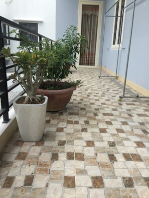 Un couloir carrelé, agrémenté d’une plante en pot et d’une rambarde en métal.
