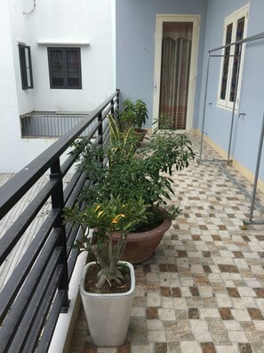 Un balcon agrémenté de plantes en pot, un sol à carreaux et une rambarde en métal.