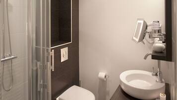 A modern bathroom with a glass shower enclosure, a toilet, and a sink with a mirror.