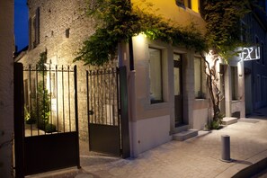 A stone building with a metal gate and a lit sign. - Vign 'appart (Nuits-Saint-Georges)