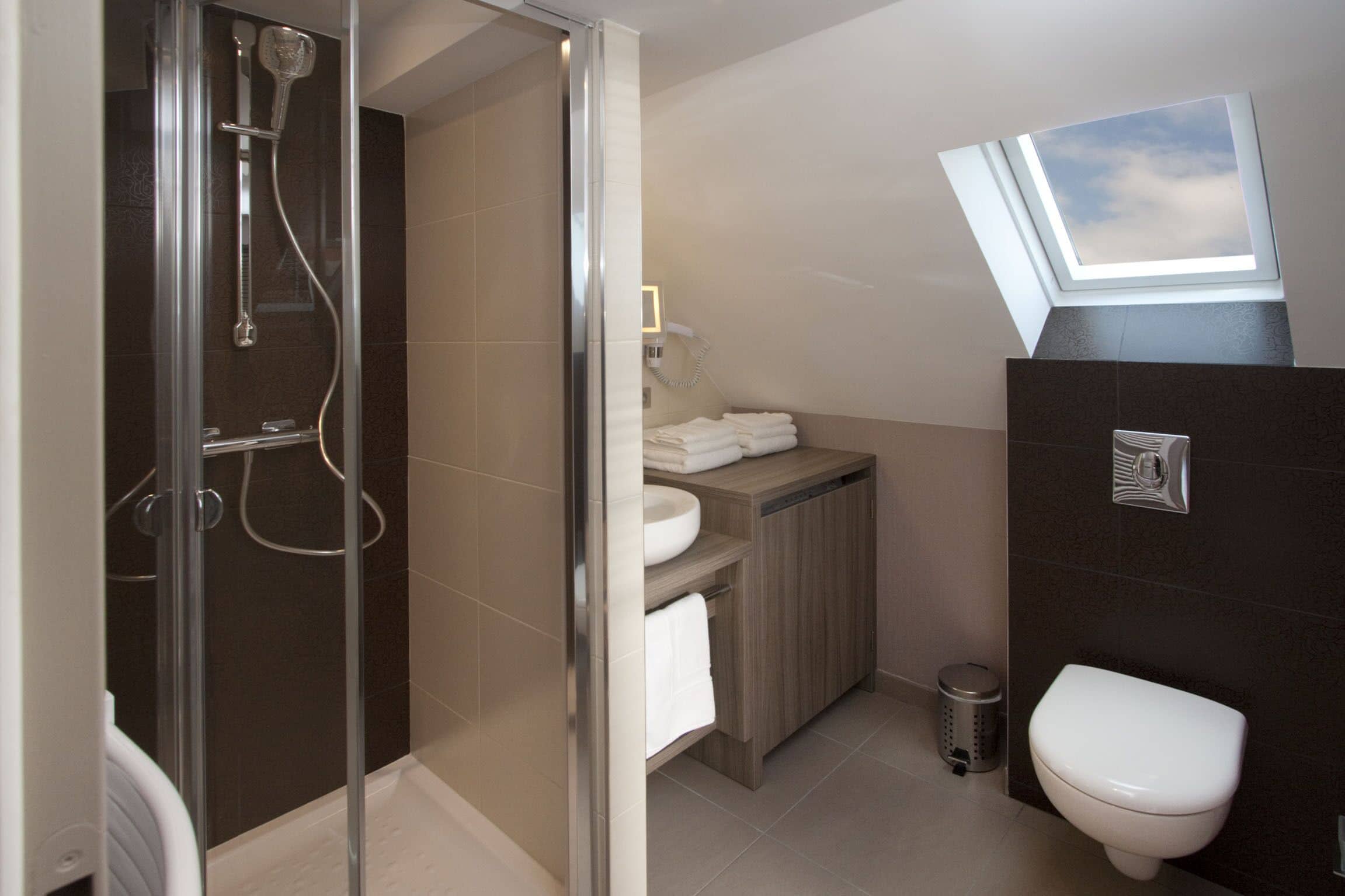 A modern bathroom with a glass-enclosed shower, a toilet, and a sink with a wooden vanity.