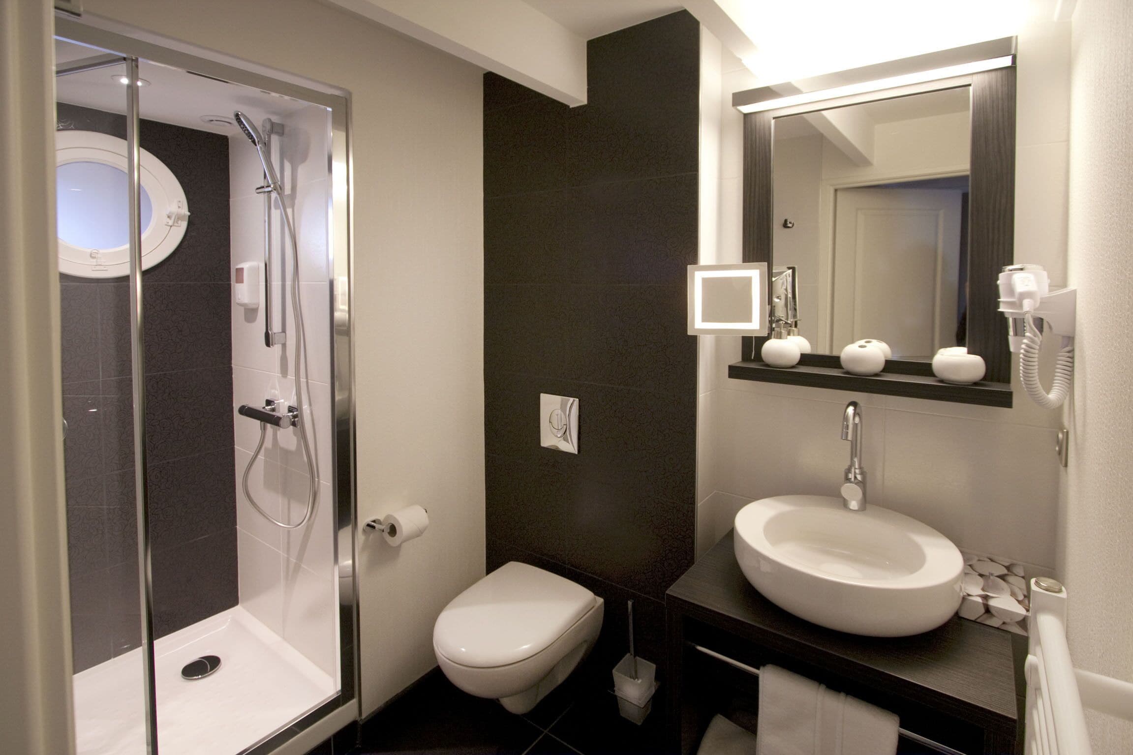 Une salle de bain moderne avec une douche à parois de verre, des toilettes, un lavabo avec un miroir et un porte-serviettes.