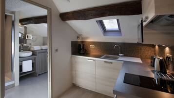A modern kitchen with a skylight, wooden beams, and a large island with a sink.