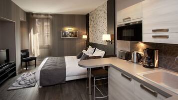 A hotel room with a bed, a desk, a microwave, a coffee maker, and a TV.