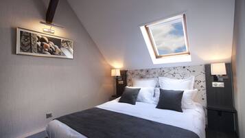 Una habitación de hotel moderna con una cama grande, un tragaluz, una obra de arte en la pared y una mesita de noche con lámpara.