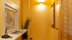 A staircase with red carpeted steps leading to a landing with a framed map and a light fixture above. - B&B DA NINA VENEZIA  (Venice)