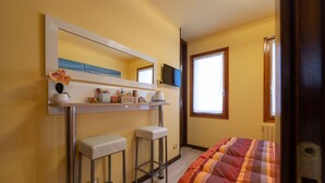 A bedroom with a bed, a desk with two stools, a mirror, a television, and a window. - B&B DA NINA VENEZIA  (Venice)