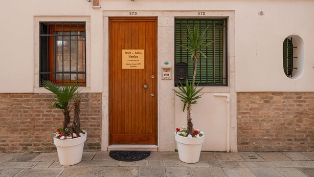 A building with a wooden door, two windows, and a sign above the door. - B&B DA NINA VENEZIA  (Venice)