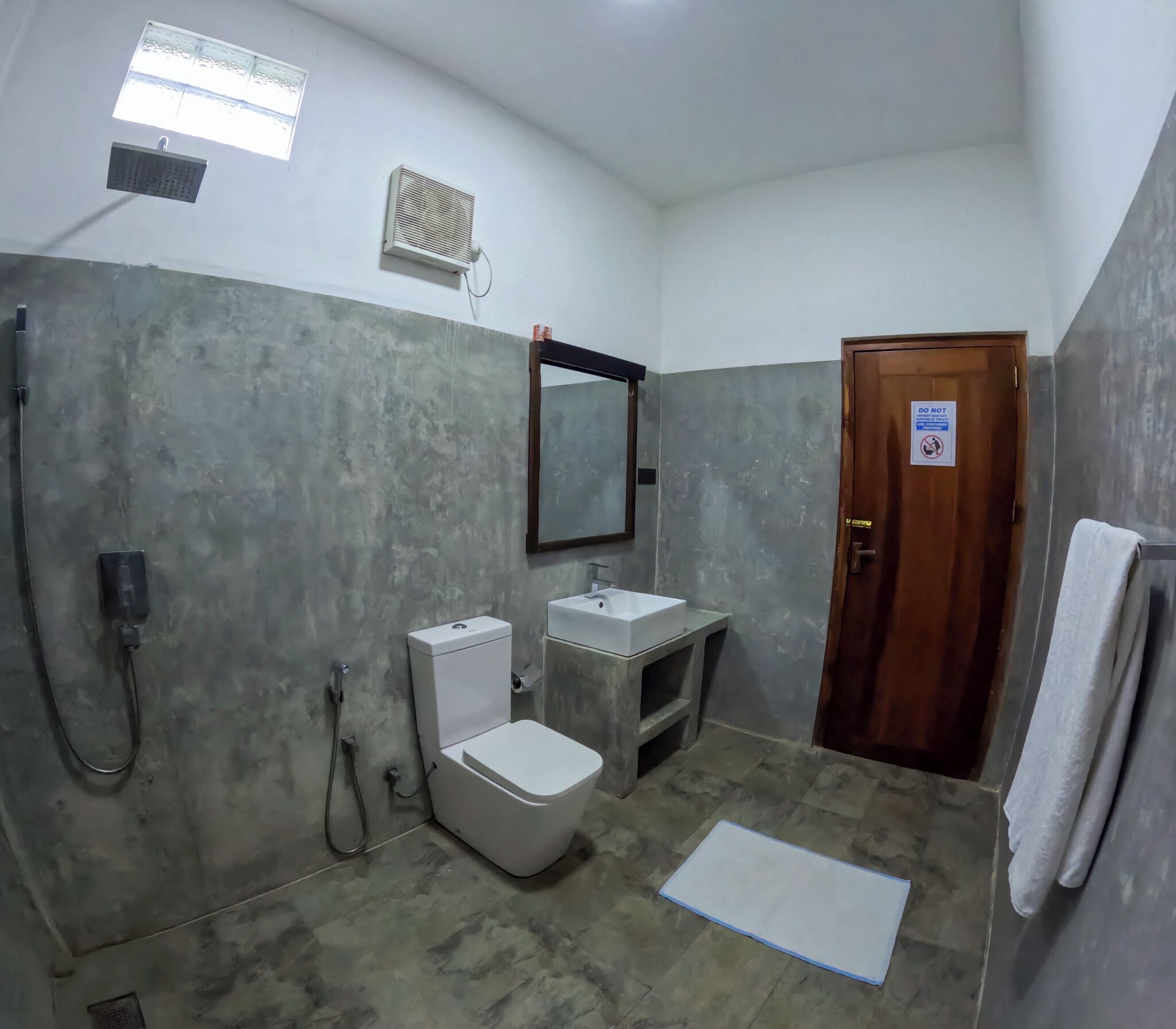A bathroom with a toilet, sink, shower, and a mirror.