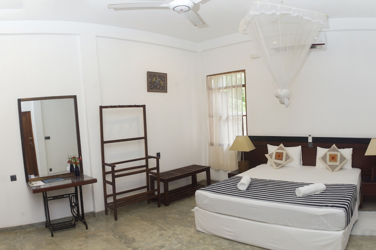 A bedroom with a bed, bedside table, mirror, and a ceiling fan.