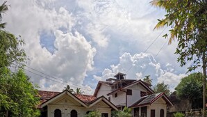 A two-story house with a red-tiled roof, a front porch, and a gravel driveway. - Surf Bay Villa (Dikwella)