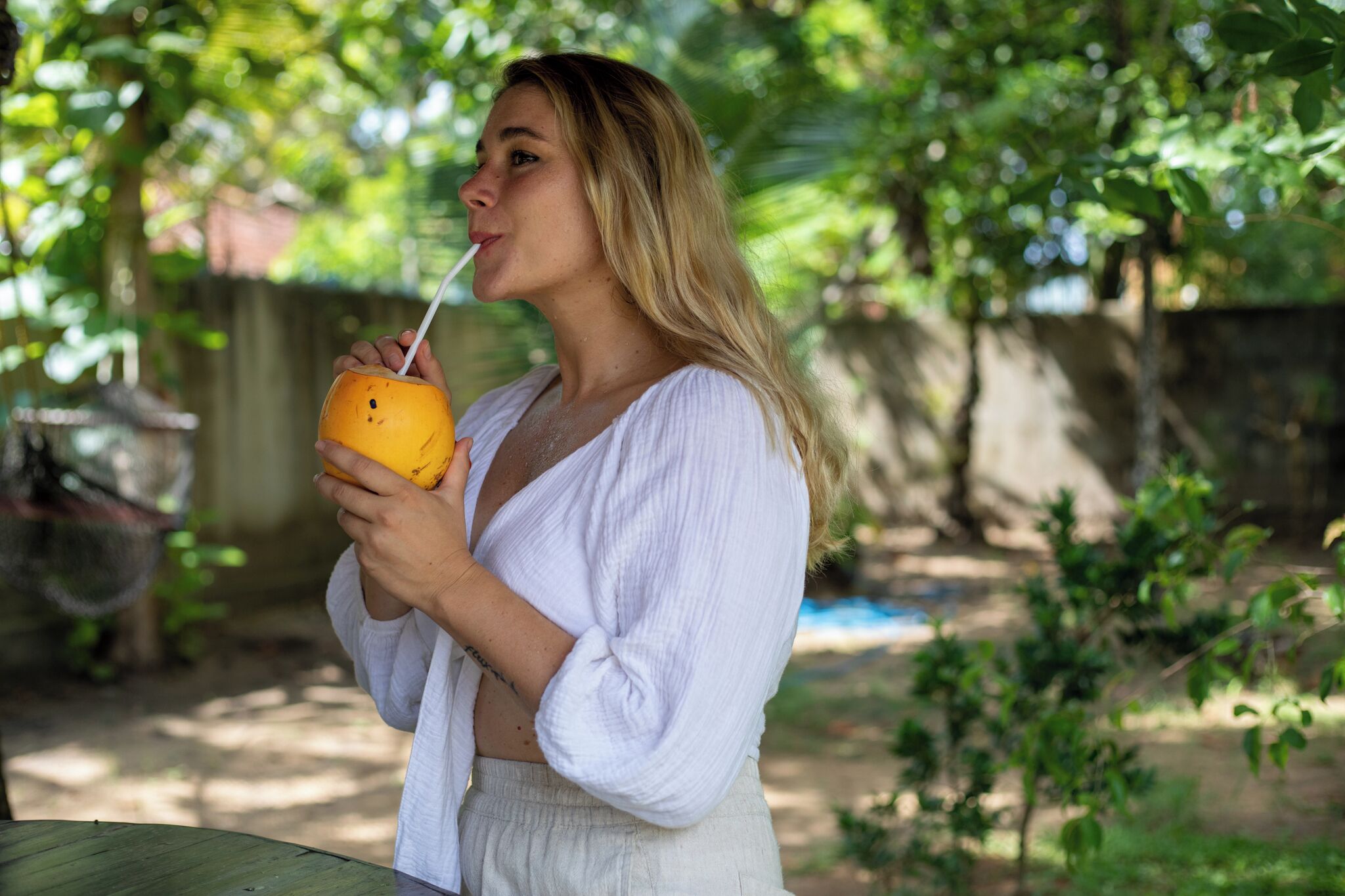 A person holding a yellow drink with a straw.