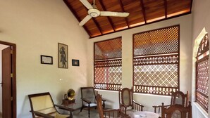 A room with a ceiling fan, wooden furniture, and decorative screens. - Surf Bay Villa (Dikwella)