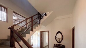 A staircase with wooden railings leading to an upper floor. A mirror and a small table are placed on the landing. - Surf Bay Villa (Dikwella)