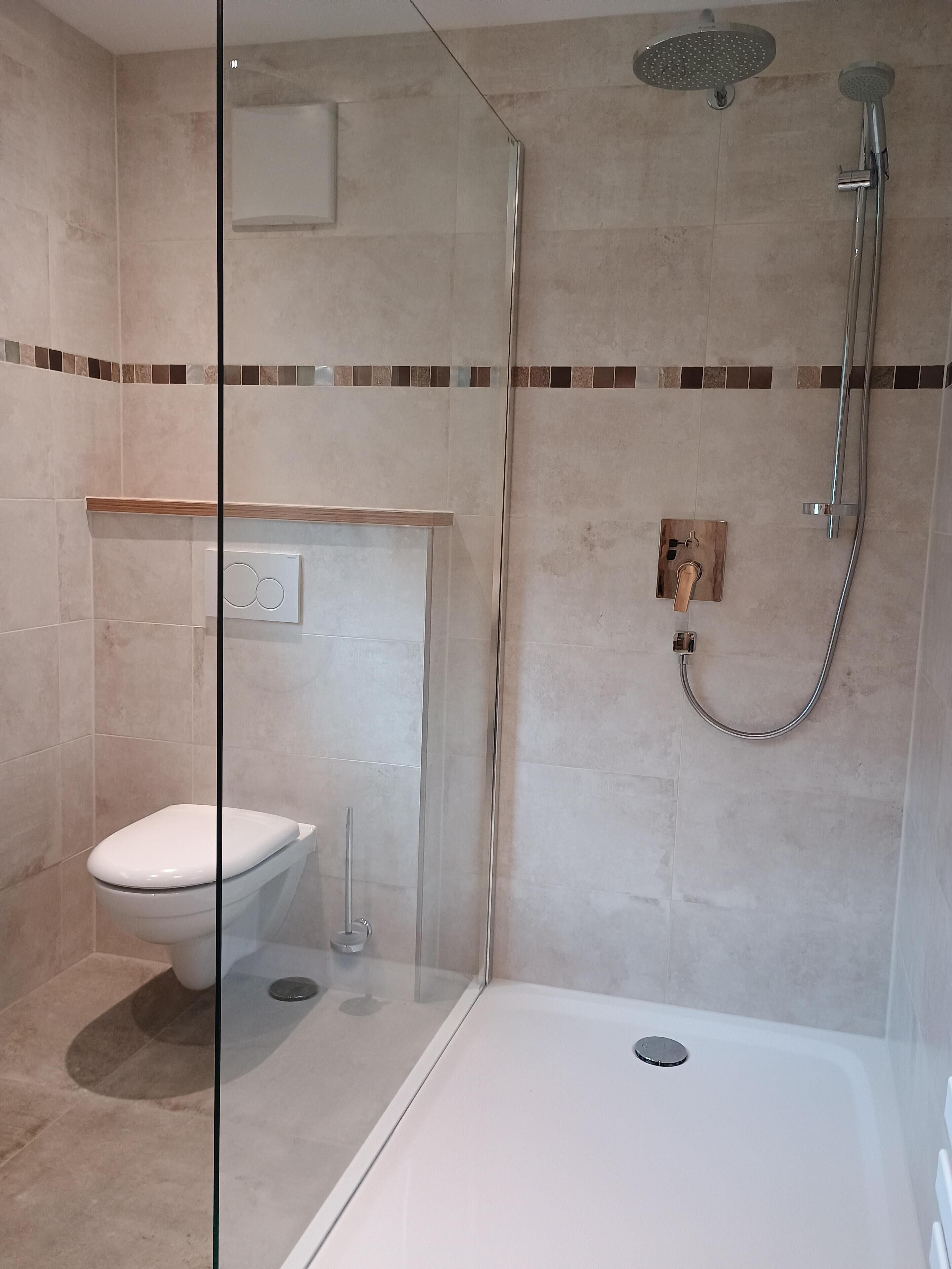 Un baño moderno con ducha de vidrio, inodoro y bañera.