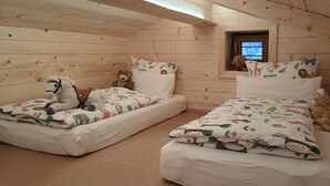 Ein gemütliches Schlafzimmer im Chalet-Stil mit zwei Einzelbetten, jeweils mit einem Plüschtier und einer gesteppten Decke.