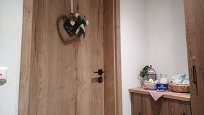 Eine Holztür mit herzförmiger Dekoration und einem kleinen Regal mit Korb, Flasche und Schachtel.