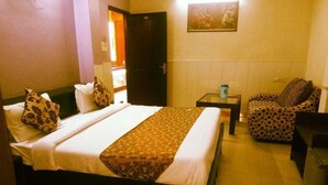 Una camera d'albergo con un letto, una sedia, un tavolino e una porta.
