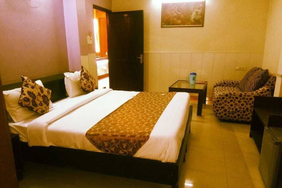 A hotel room with a bed, a chair, a small table, and a door.