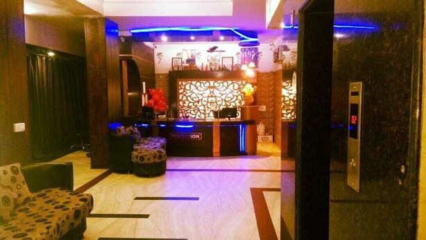 Una hall d'albergo con reception, zona salotto e ascensore.